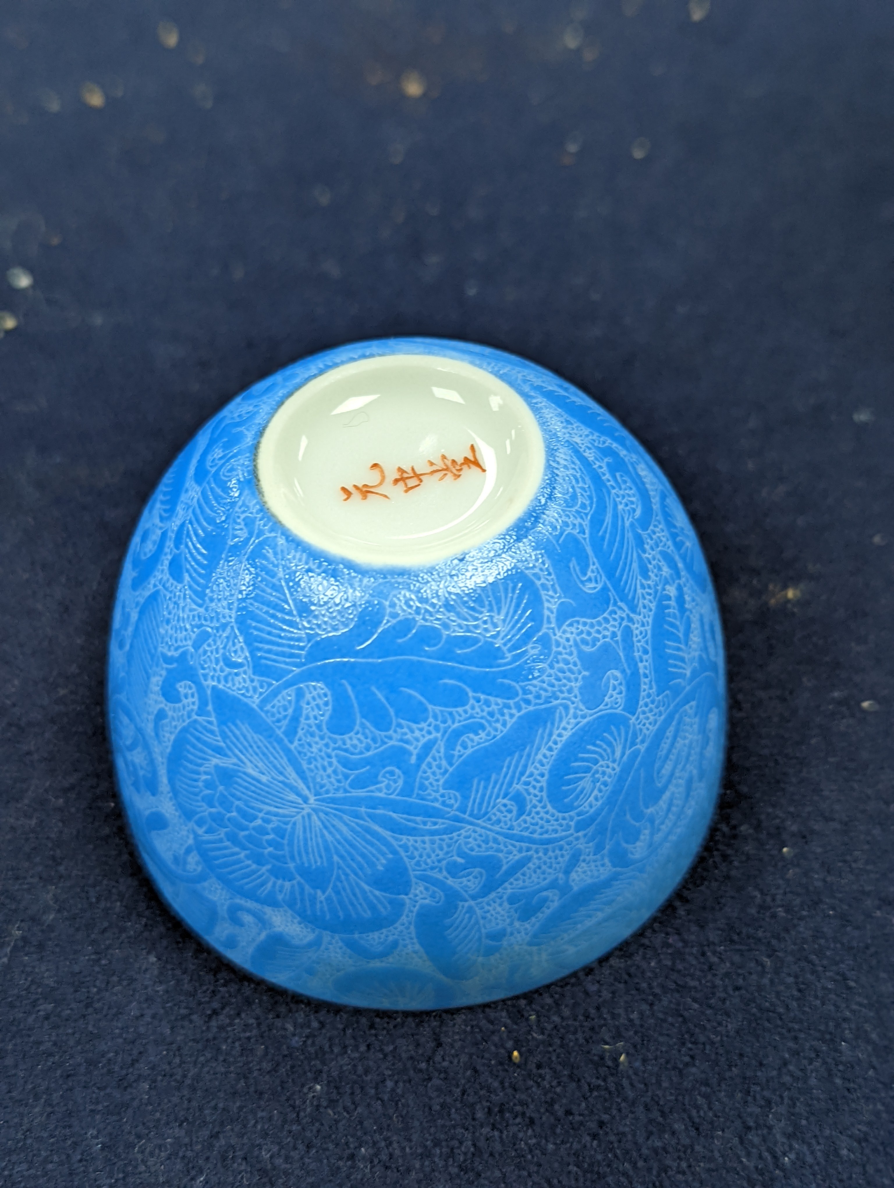 A Japanese or Chinese sgrafitto blue enamelled cup, cased. 6cm diameter